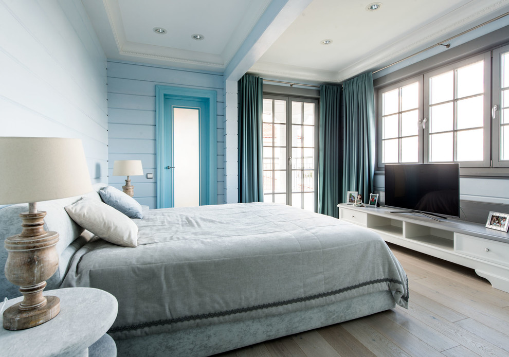 Idée de décoration pour une chambre d'amis design de taille moyenne avec parquet clair, aucune cheminée et un mur bleu.