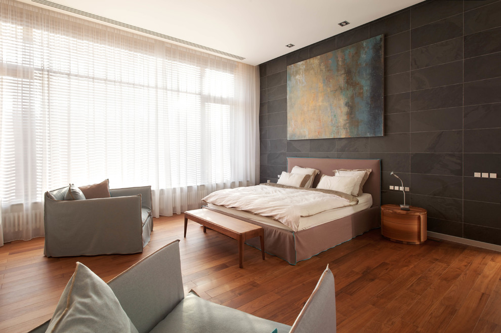 Modelo de dormitorio principal actual grande con paredes negras, suelo de madera en tonos medios y suelo marrón