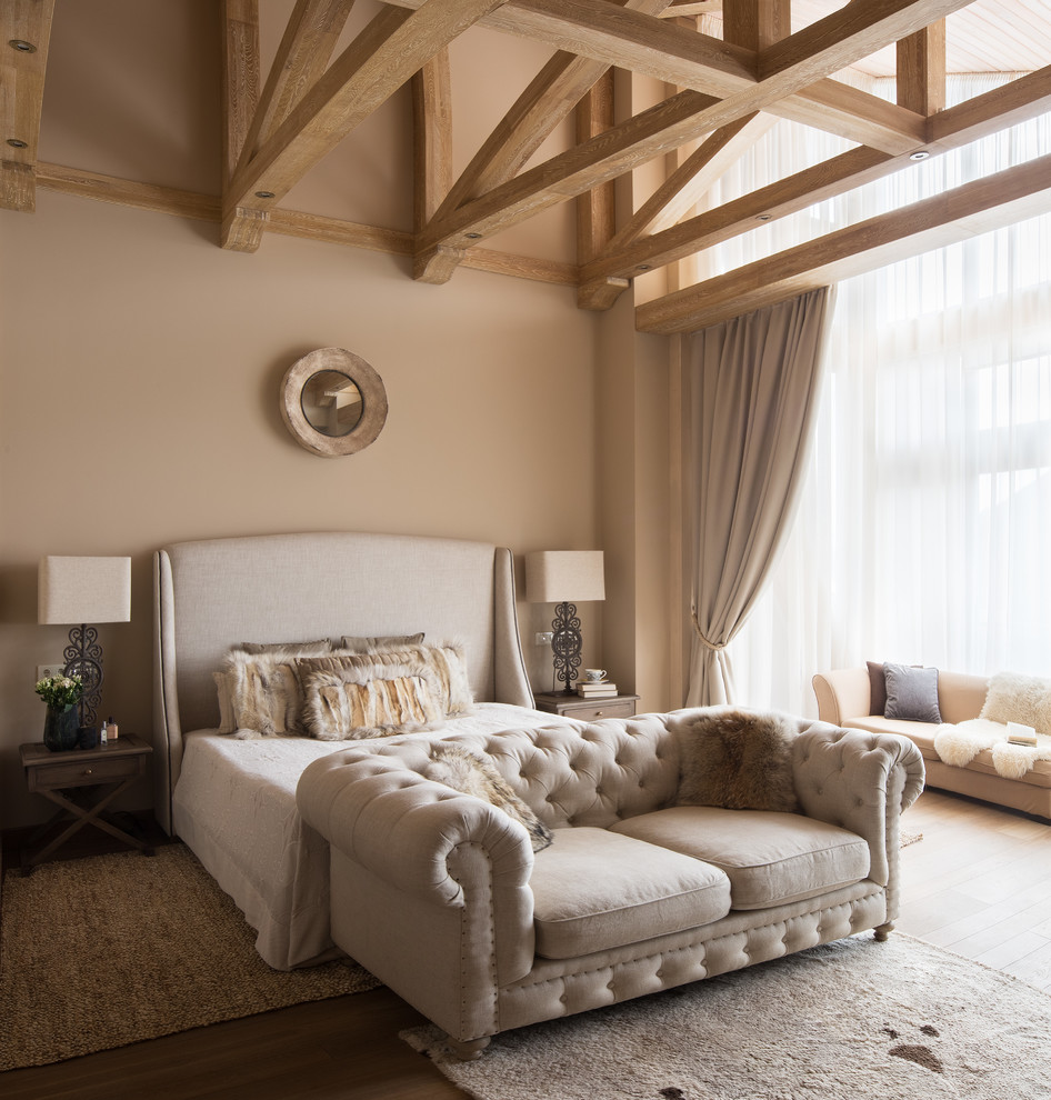 На фото: хозяйская спальня: освещение в стиле неоклассика (современная классика) с бежевыми стенами и коричневым полом