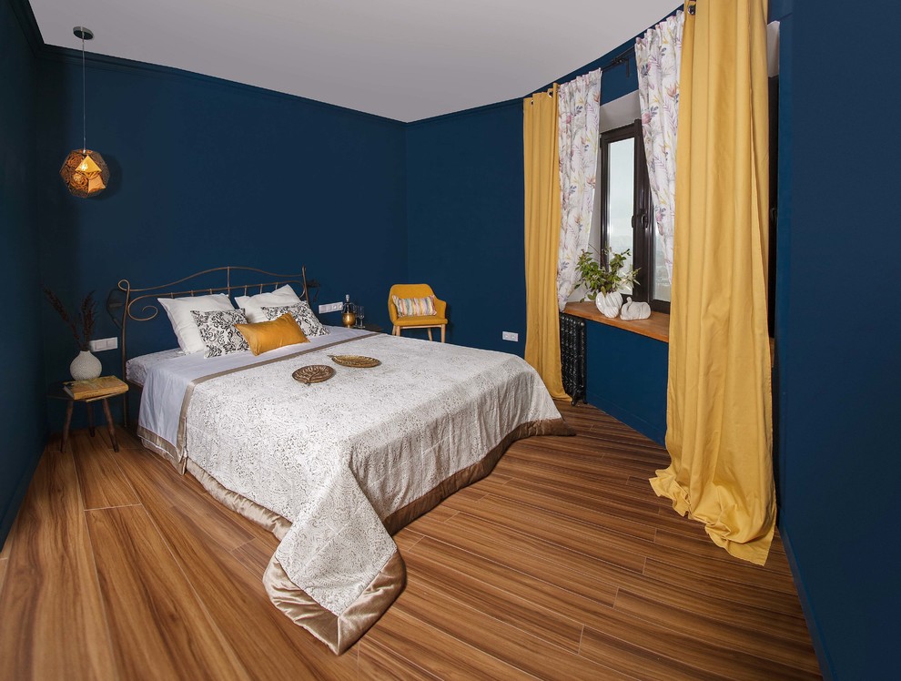 Diseño de dormitorio principal bohemio de tamaño medio con paredes azules y suelo laminado