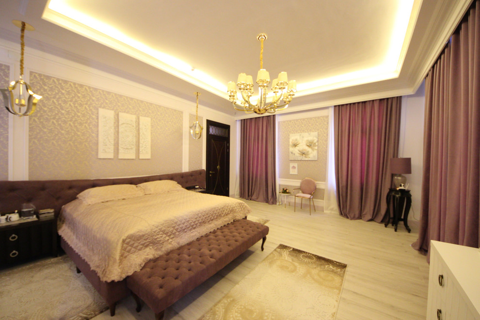 Ejemplo de dormitorio principal ecléctico grande con paredes púrpuras, suelo de madera en tonos medios, chimenea lineal, marco de chimenea de piedra, suelo beige, bandeja y papel pintado