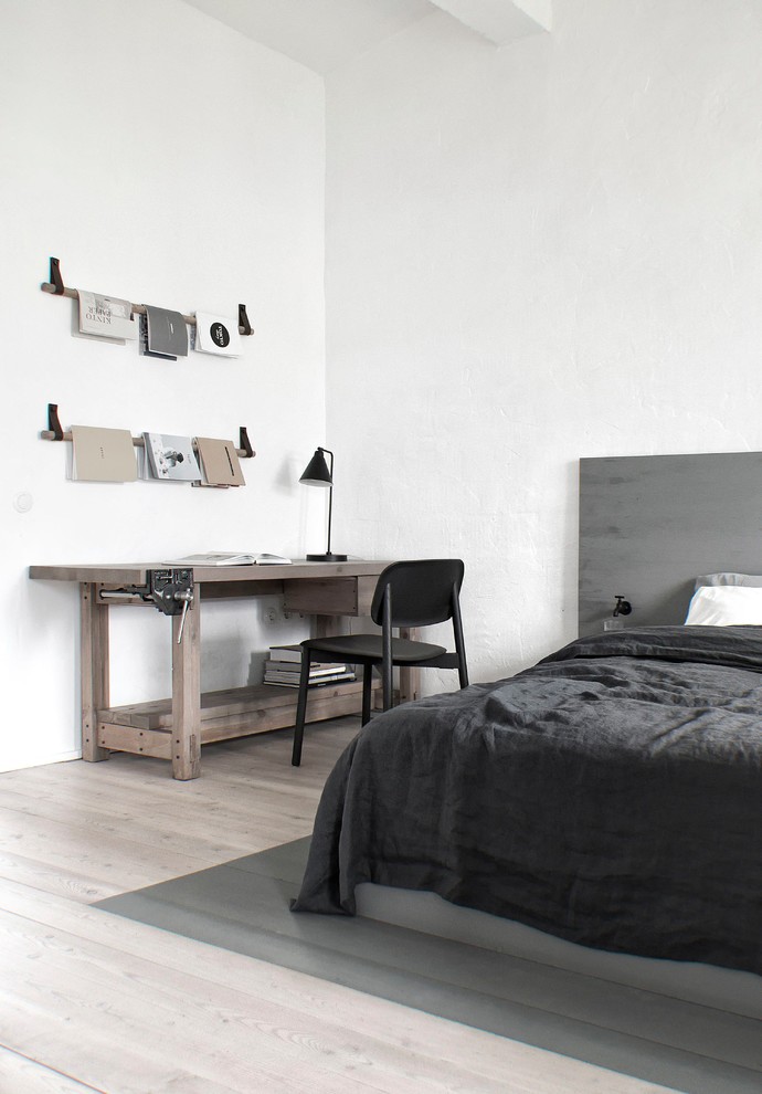 Immagine di una piccola camera matrimoniale industriale con pareti bianche, pavimento beige e parquet chiaro