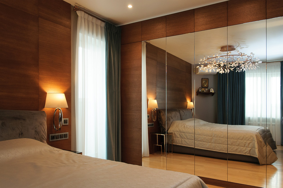 На фото: хозяйская спальня в современном стиле с светлым паркетным полом без камина с