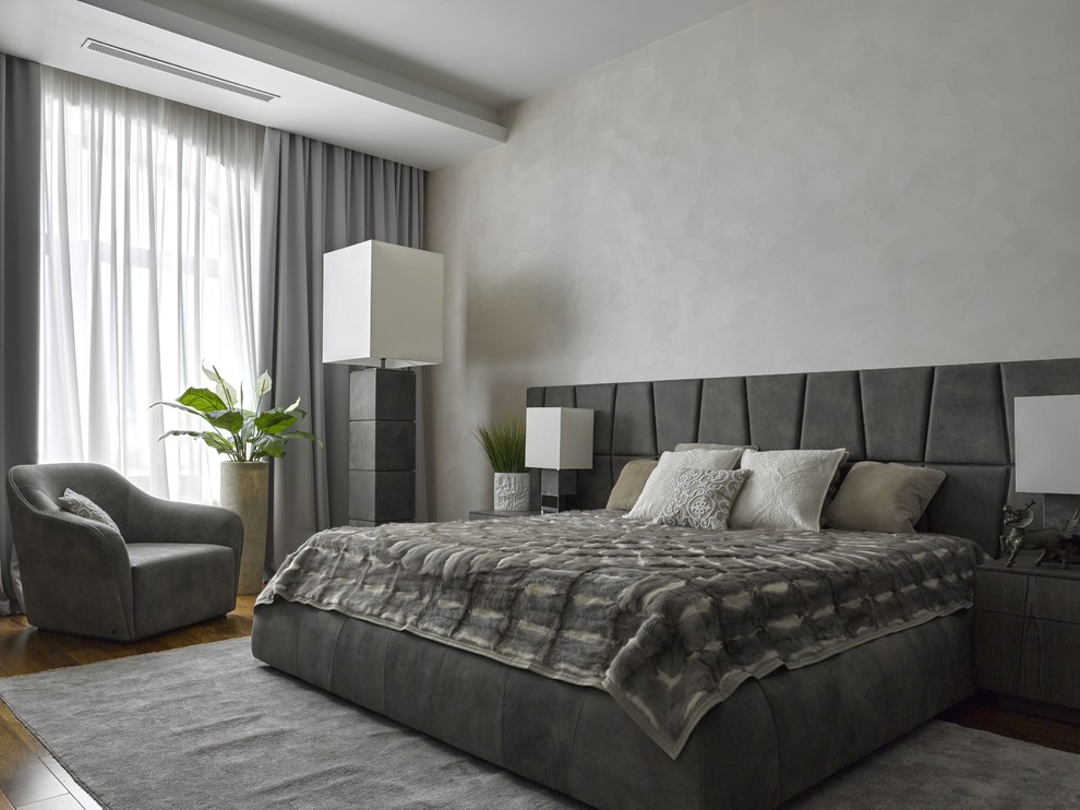 This is an example of a large contemporary master bedroom in Moscow with grey walls, medium hardwood flooring and feature lighting.