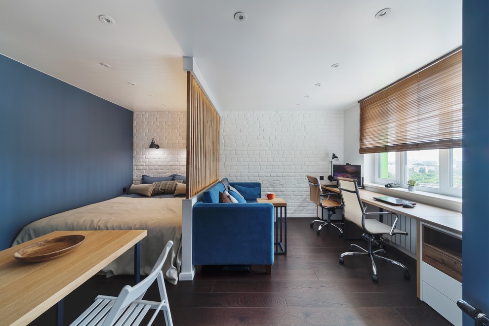 На фото: спальня в современном стиле с синими стенами, темным паркетным полом, коричневым полом и зонированием шторами