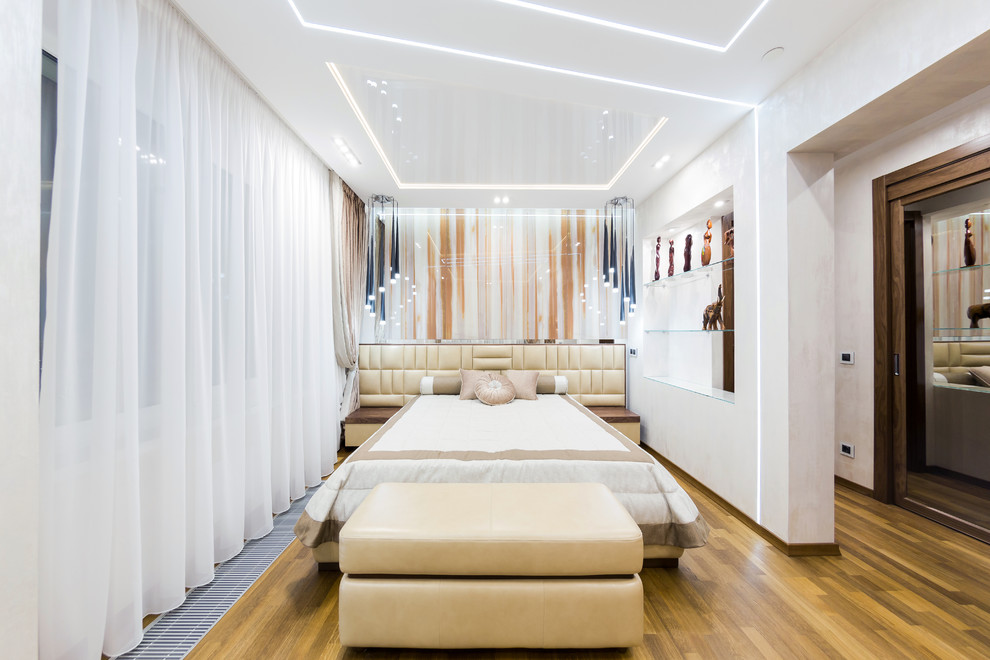 Imagen de dormitorio principal contemporáneo de tamaño medio sin chimenea con paredes blancas y suelo de madera en tonos medios