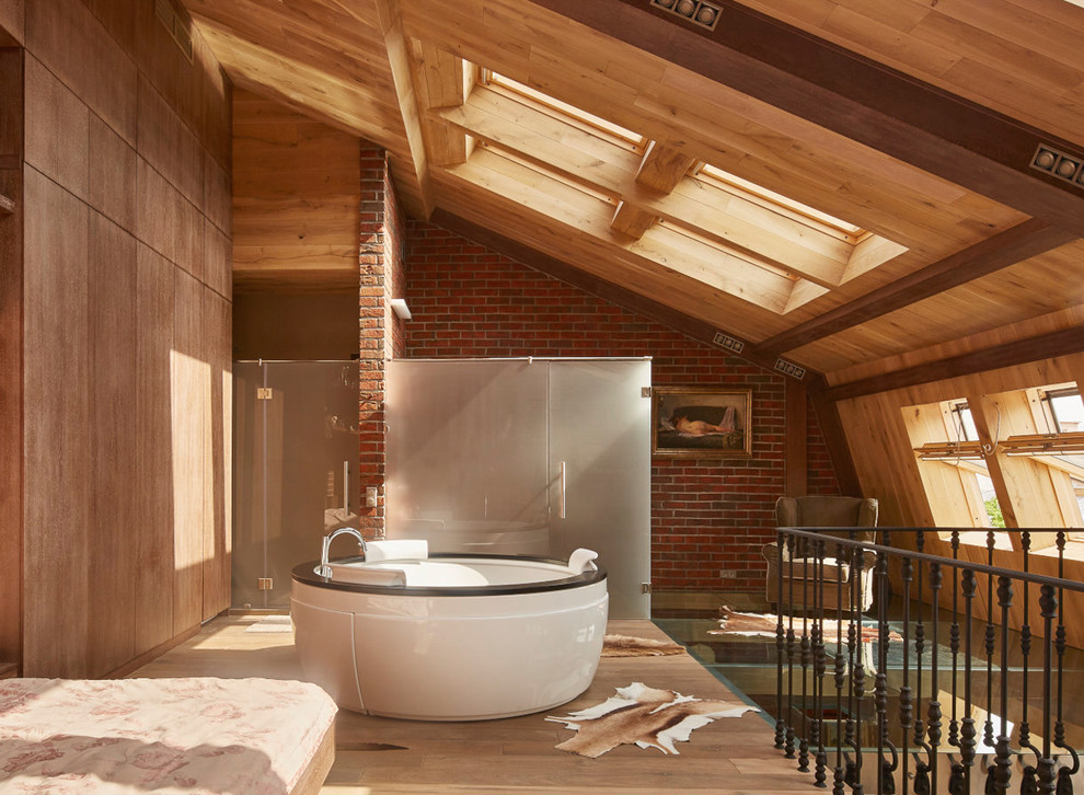 На фото: хозяйская спальня на мансарде в стиле фьюжн с коричневыми стенами и паркетным полом среднего тона с