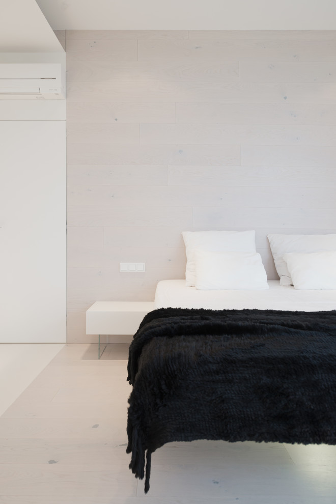 Ejemplo de dormitorio principal contemporáneo de tamaño medio con suelo de madera clara y paredes blancas