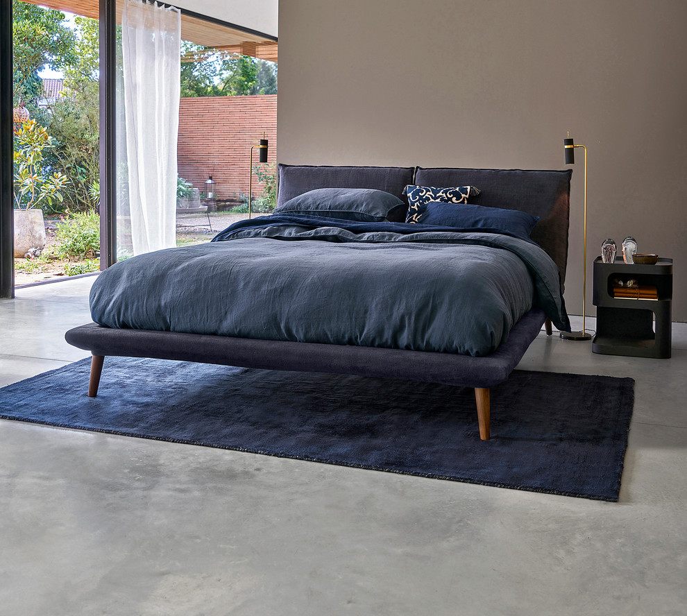 Modelo de dormitorio principal actual sin chimenea con suelo gris, paredes marrones y suelo de cemento