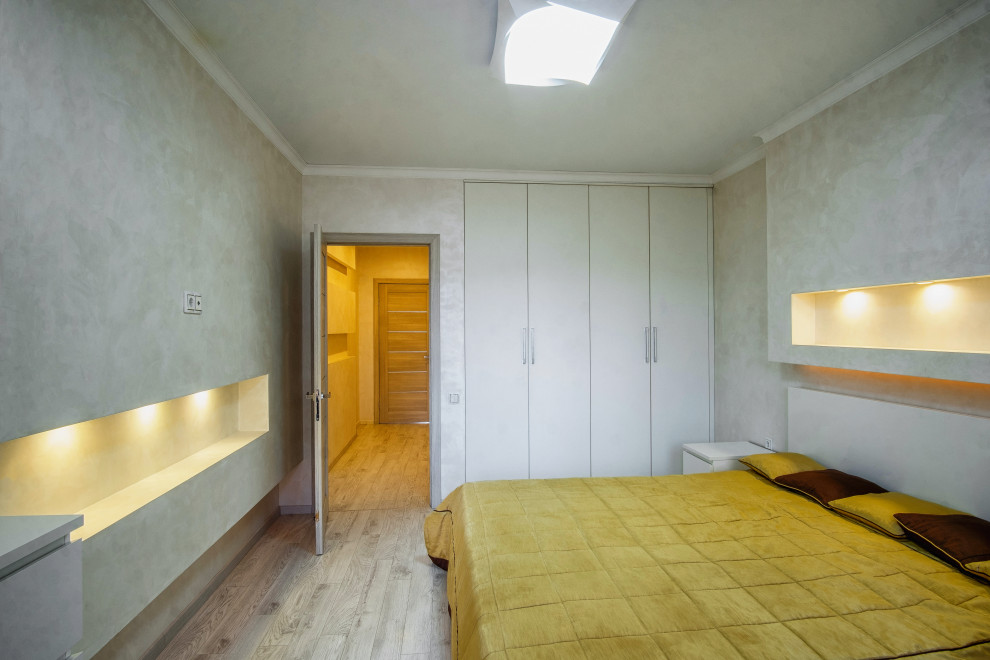 На фото: хозяйская спальня среднего размера в современном стиле с желтыми стенами, полом из ламината и серым полом