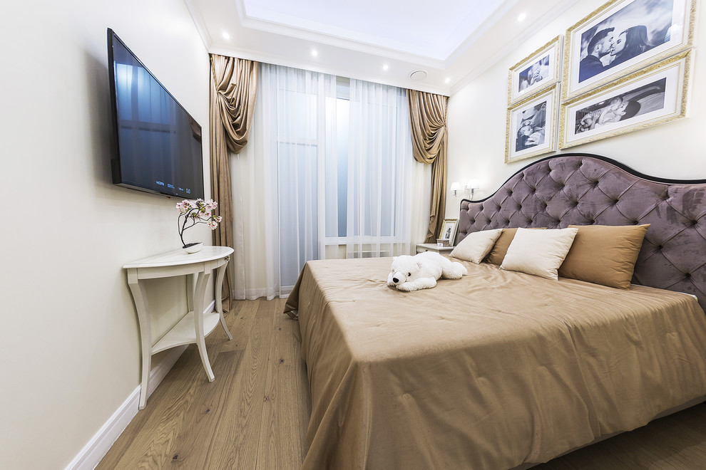 Modelo de dormitorio principal tradicional de tamaño medio con paredes beige y suelo de madera en tonos medios