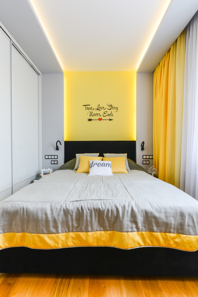 This is an example of a medium sized contemporary master and grey and yellow bedroom in Other with grey walls and medium hardwood flooring.