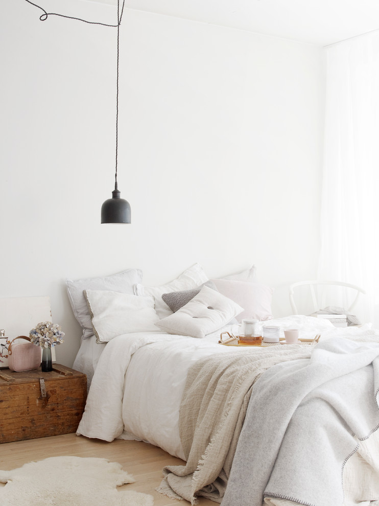 На фото: хозяйская спальня в скандинавском стиле с белыми стенами, светлым паркетным полом и бежевым полом