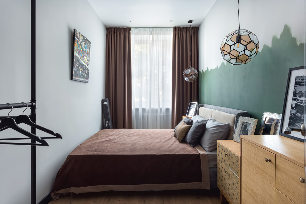 Diseño de dormitorio principal escandinavo pequeño con paredes verdes, suelo laminado y suelo marrón