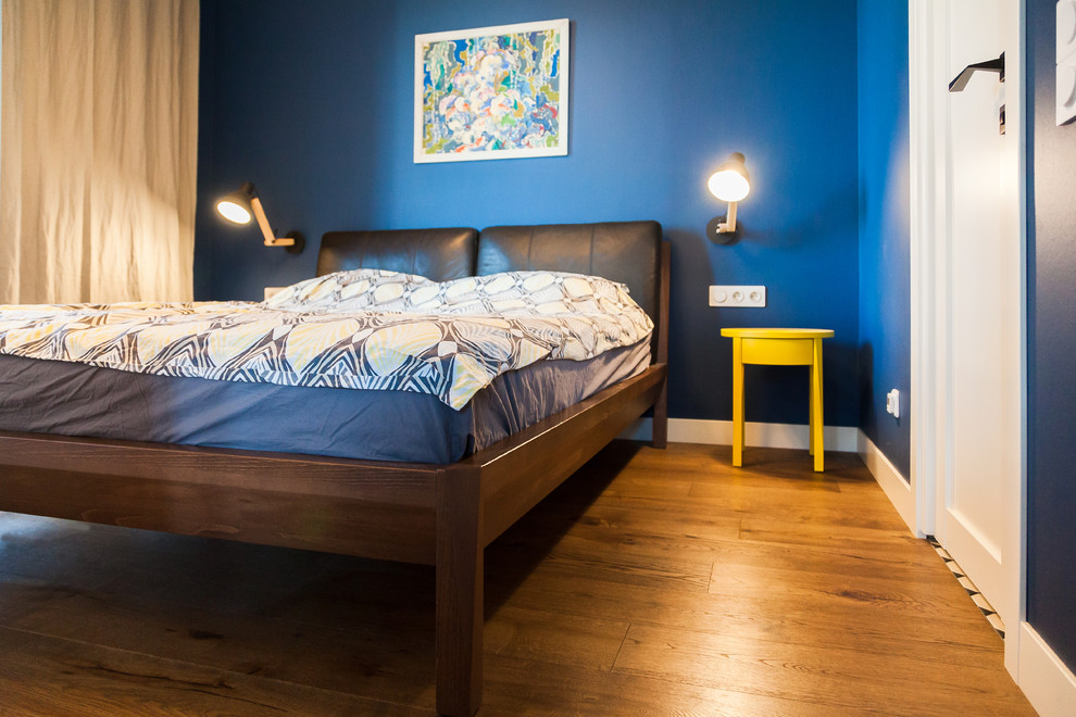Diseño de dormitorio escandinavo pequeño con paredes azules, suelo de madera en tonos medios y suelo marrón