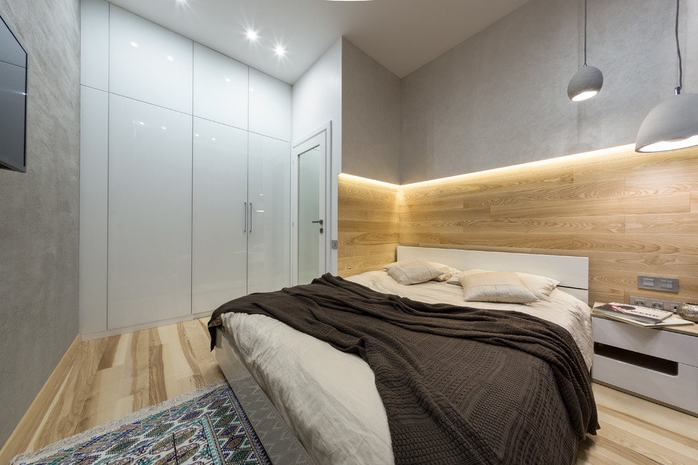Cette photo montre une chambre parentale tendance de taille moyenne avec un mur gris et parquet clair.
