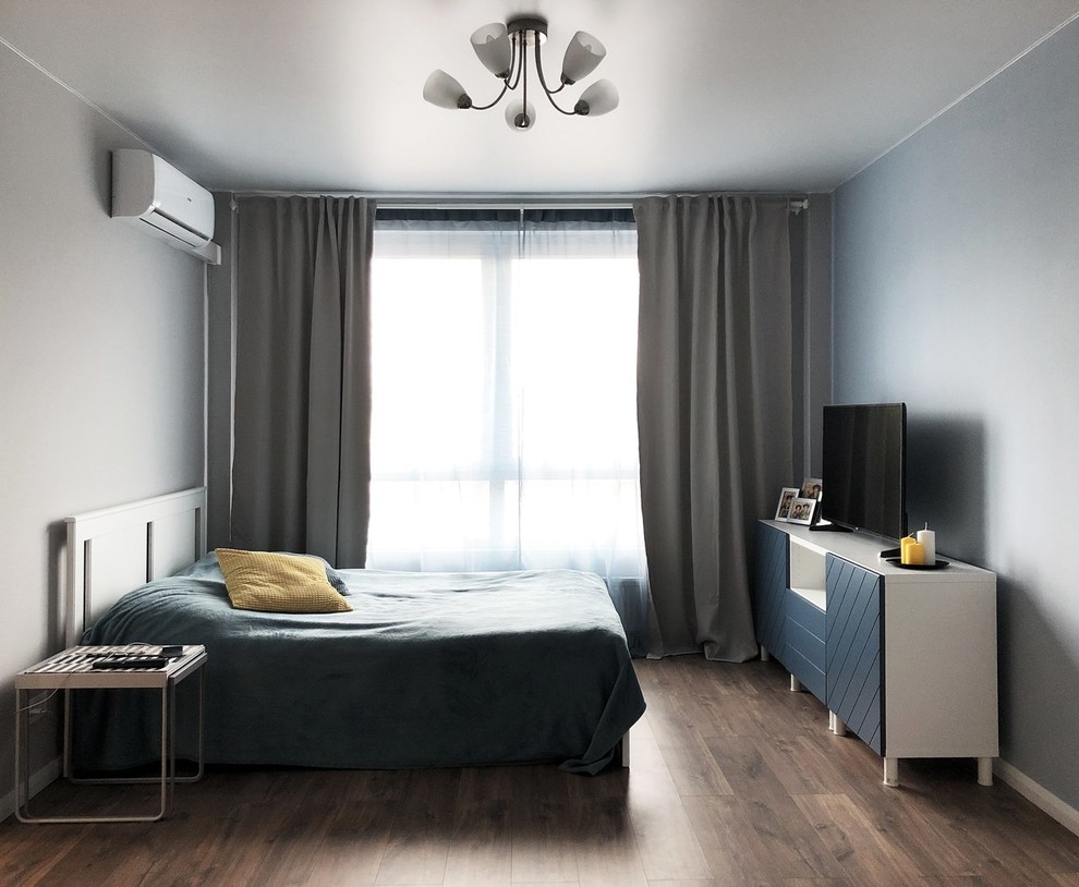 Imagen de dormitorio principal escandinavo de tamaño medio sin chimenea con paredes grises, suelo laminado y suelo marrón