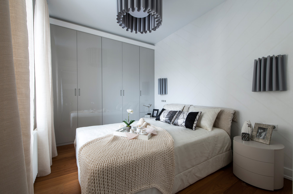 Aménagement d'une petite chambre parentale contemporaine avec un mur blanc et un sol en bois brun.