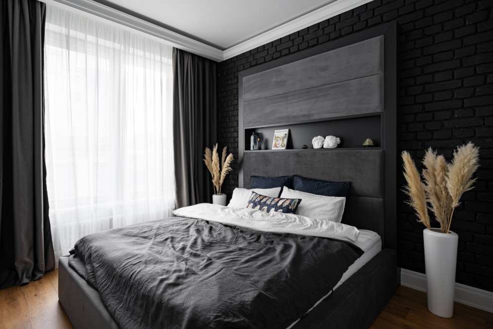 Aménagement d'une chambre parentale grise et noire contemporaine de taille moyenne avec un mur noir, un sol en bois brun, un plafond décaissé et un mur en parement de brique.