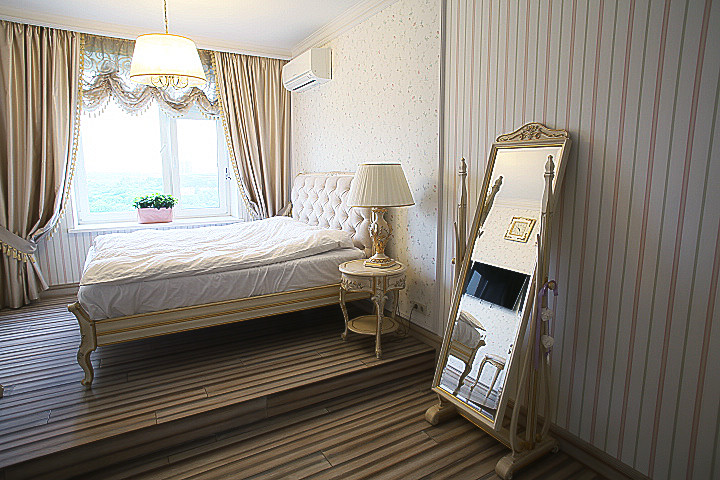 Klassisk inredning av ett stort sovrum, med flerfärgade väggar, ljust trägolv och flerfärgat golv