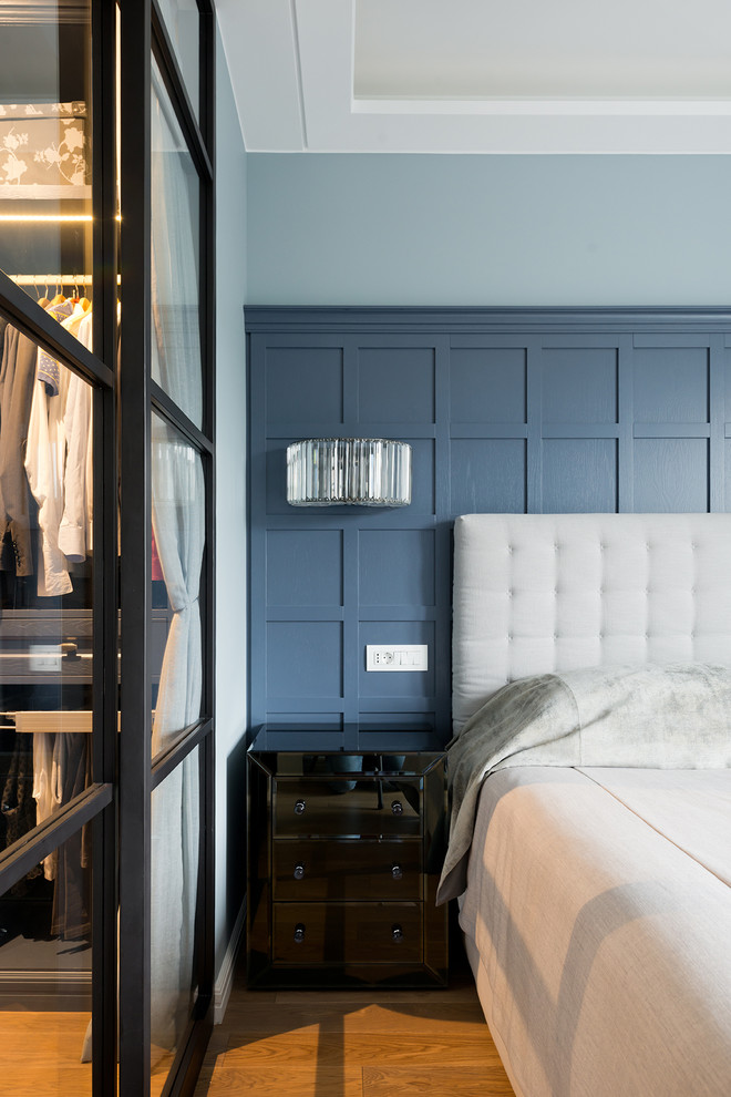 Cette image montre une petite chambre parentale design avec un mur bleu et un sol en bois brun.