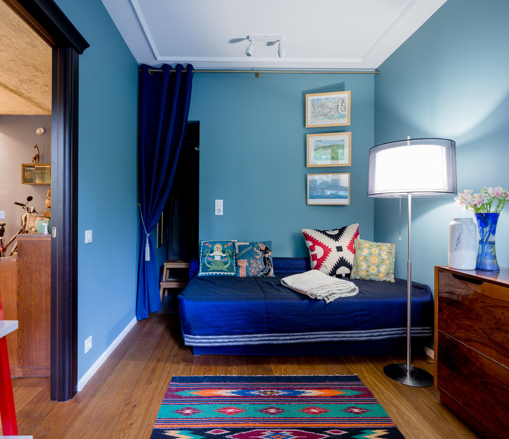 Inspiration pour une chambre minimaliste avec un mur bleu, un sol en bois brun et dressing.