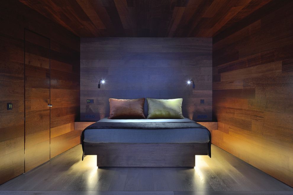 Idée de décoration pour une chambre parentale design de taille moyenne avec un mur marron et un sol en bois brun.