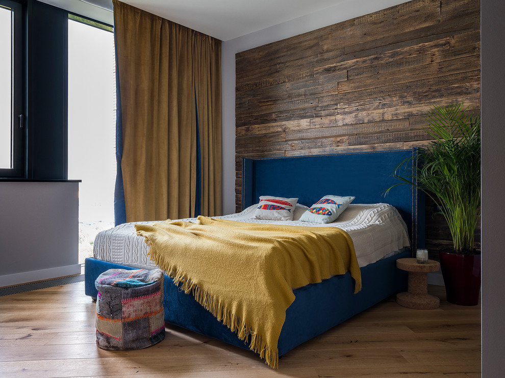 Immagine di una camera da letto design con pareti grigie, pavimento in legno massello medio e pavimento marrone