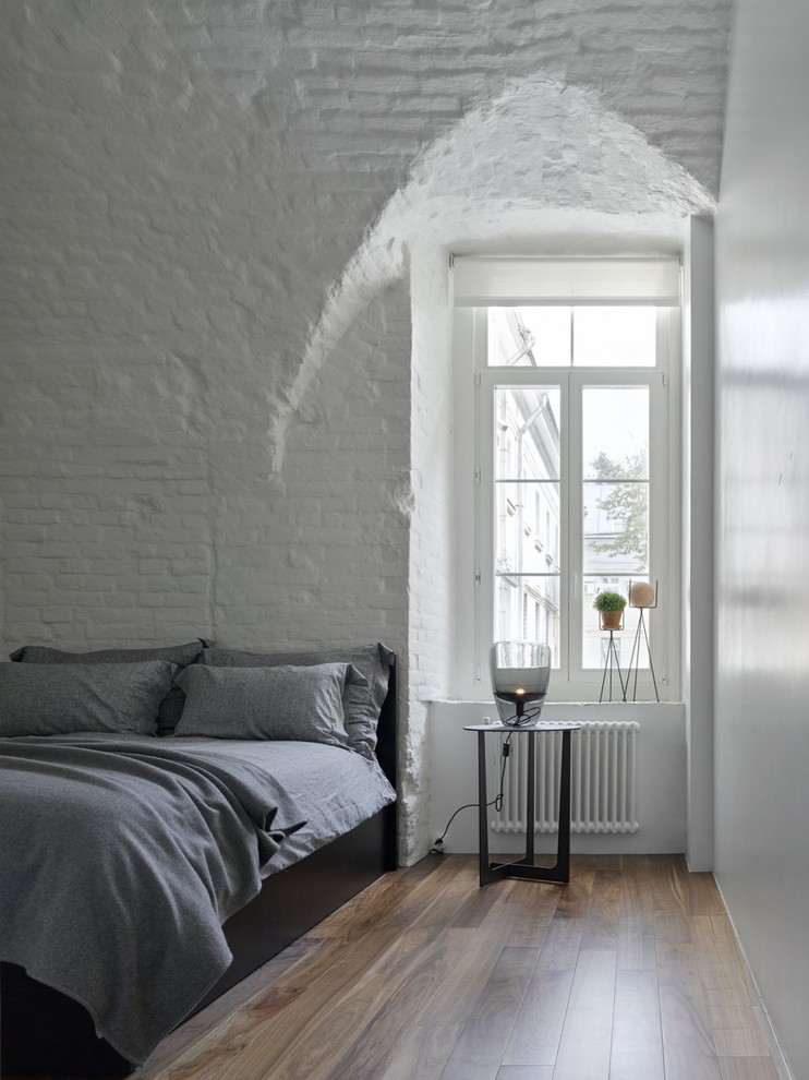 Inspiration pour une chambre parentale design avec un mur blanc, parquet foncé et un sol marron.