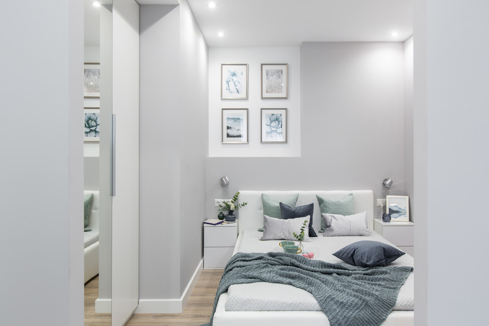 Стильный дизайн: маленькая хозяйская спальня в современном стиле с серыми стенами, полом из ламината и коричневым полом для на участке и в саду - последний тренд