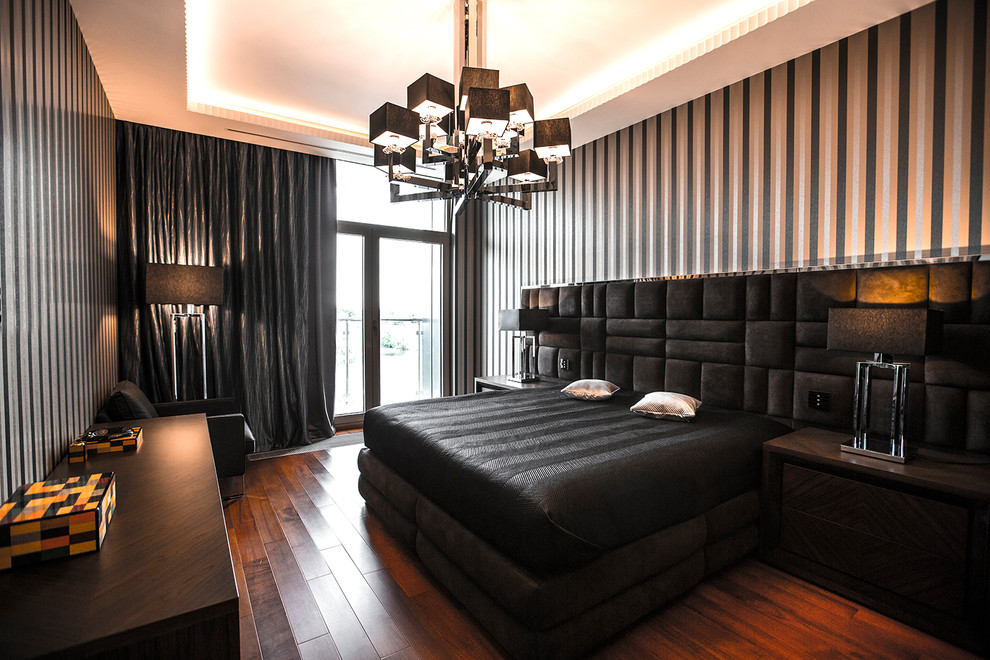 На фото: хозяйская спальня в современном стиле с черными стенами, паркетным полом среднего тона, коричневым полом и кроватью в нише с