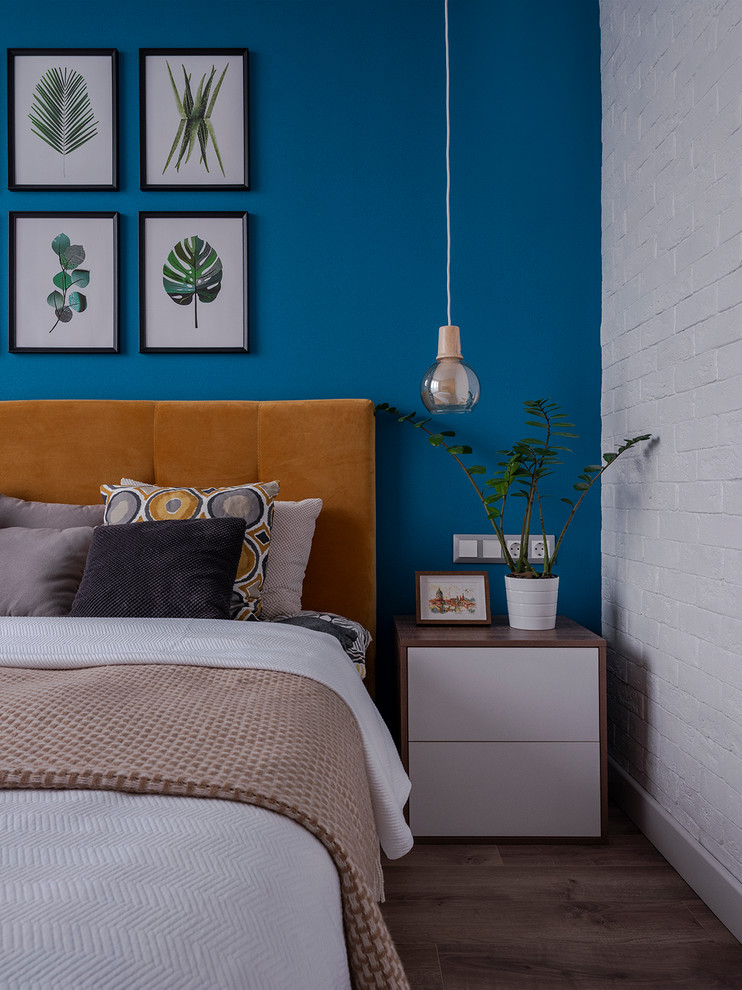 Inspiration pour une chambre parentale design avec un mur bleu, parquet foncé et un sol marron.