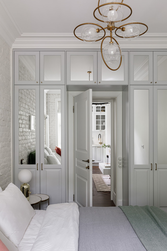 Immagine di una camera matrimoniale scandinava di medie dimensioni con pareti bianche, pavimento in vinile, pavimento marrone e pareti in mattoni