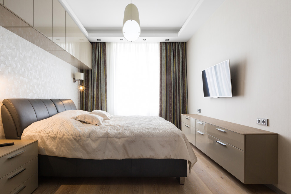 Modernes Hauptschlafzimmer ohne Kamin mit weißer Wandfarbe und braunem Holzboden in Sankt Petersburg