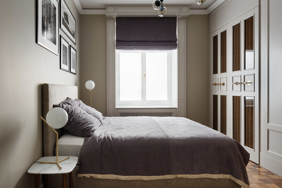 Modelo de dormitorio clásico renovado con paredes beige, suelo de madera en tonos medios y suelo marrón