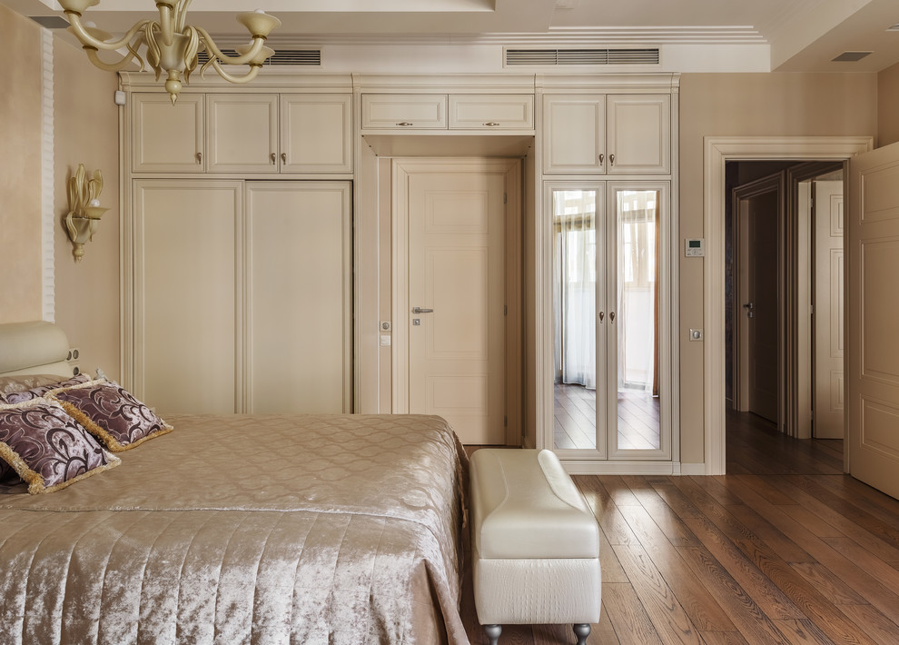 Ejemplo de dormitorio principal clásico renovado con paredes beige, suelo de madera en tonos medios y suelo marrón