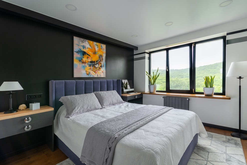 Modelo de dormitorio contemporáneo sin chimenea con paredes negras y suelo de madera en tonos medios