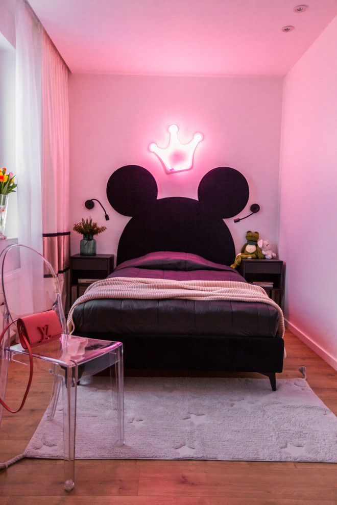 Modelo de dormitorio actual con paredes rosas, suelo de madera en tonos medios y suelo marrón