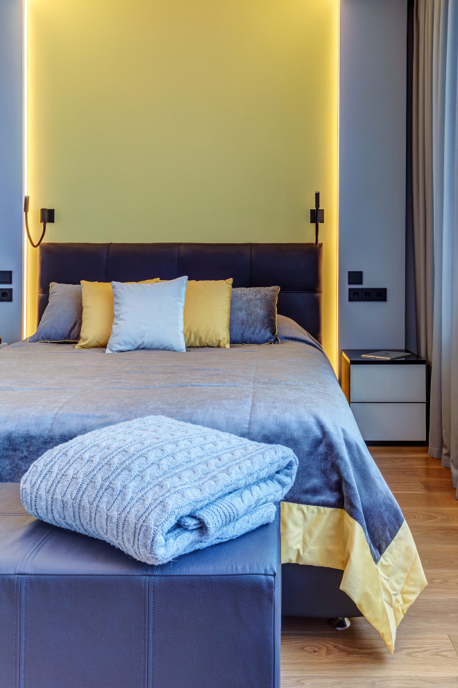 Modelo de dormitorio principal contemporáneo pequeño con paredes grises, suelo de madera en tonos medios y suelo beige