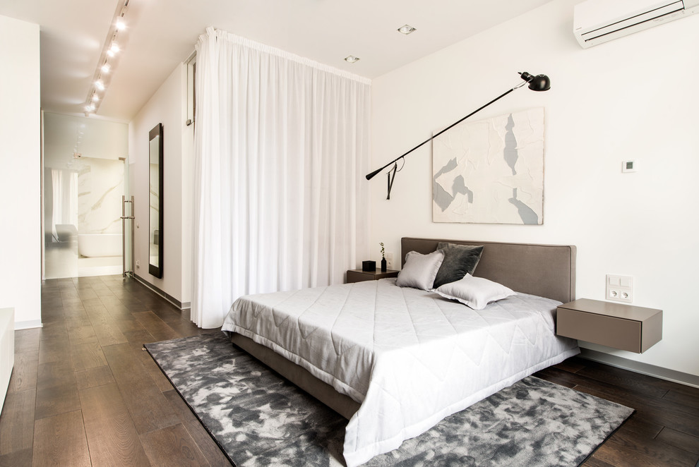 Стильный дизайн: хозяйская спальня: освещение в современном стиле с белыми стенами, темным паркетным полом, коричневым полом и кроватью в нише - последний тренд