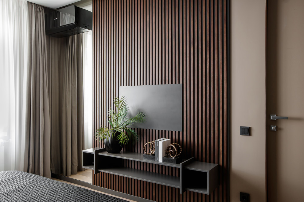 Ejemplo de dormitorio principal actual de tamaño medio con paredes grises y suelo de madera en tonos medios