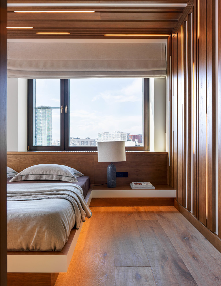 На фото: хозяйская спальня в современном стиле с паркетным полом среднего тона и коричневым полом
