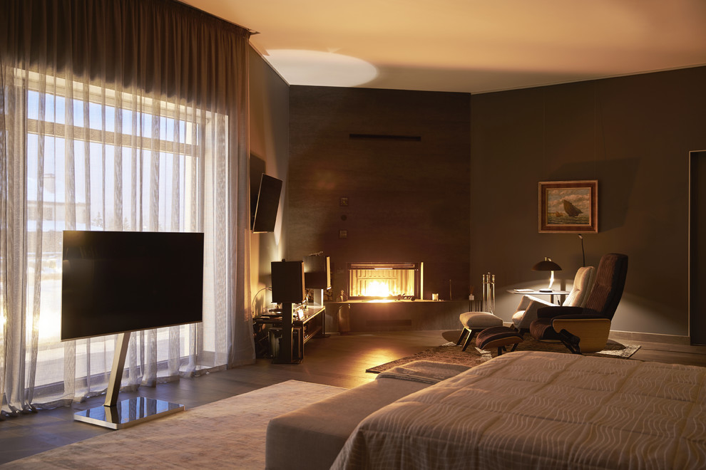 На фото: хозяйская спальня в современном стиле с угловым камином, коричневыми стенами и коричневым полом