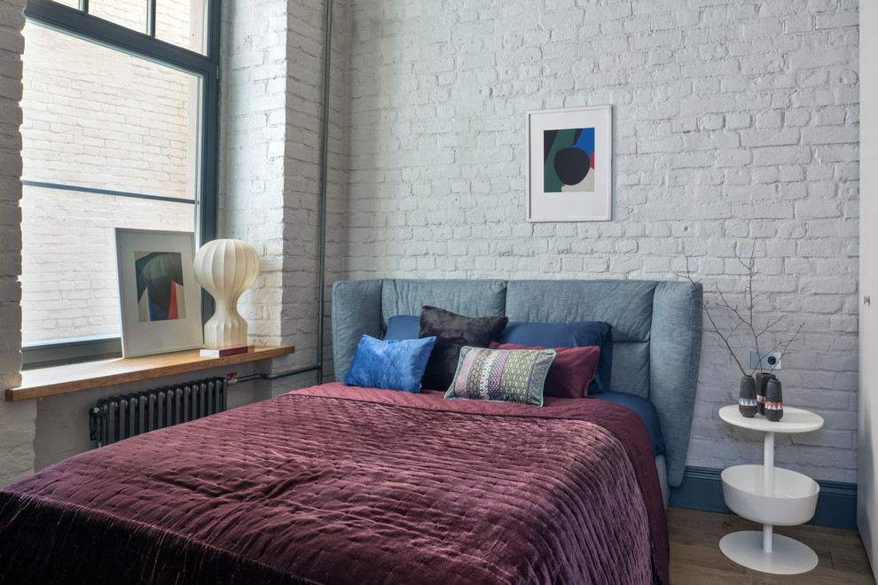 Urban master medium tone wood floor, brown floor and brick wall bedroom photo in Moscow with white walls
