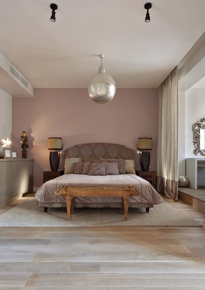 Modelo de dormitorio principal ecléctico con paredes rosas y suelo de madera clara