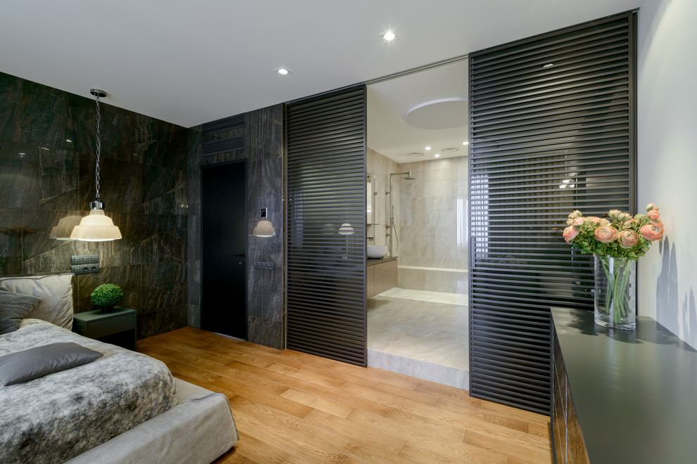 Idée de décoration pour une chambre parentale design avec un sol en bois brun et un mur noir.