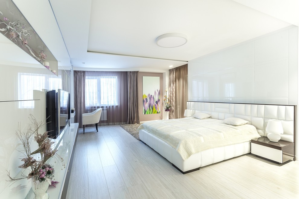Large contemporary guest bedroom in Other with white walls, light hardwood flooring and beige floors.