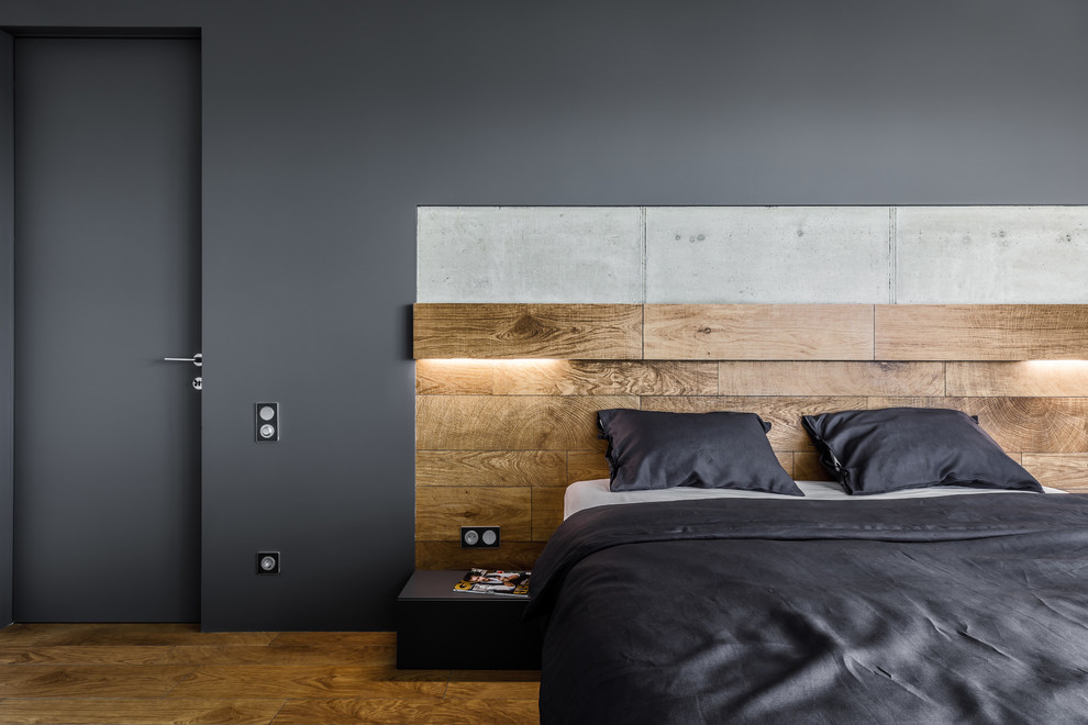 Photo of a contemporary master bedroom in Other with black walls and brown floors.