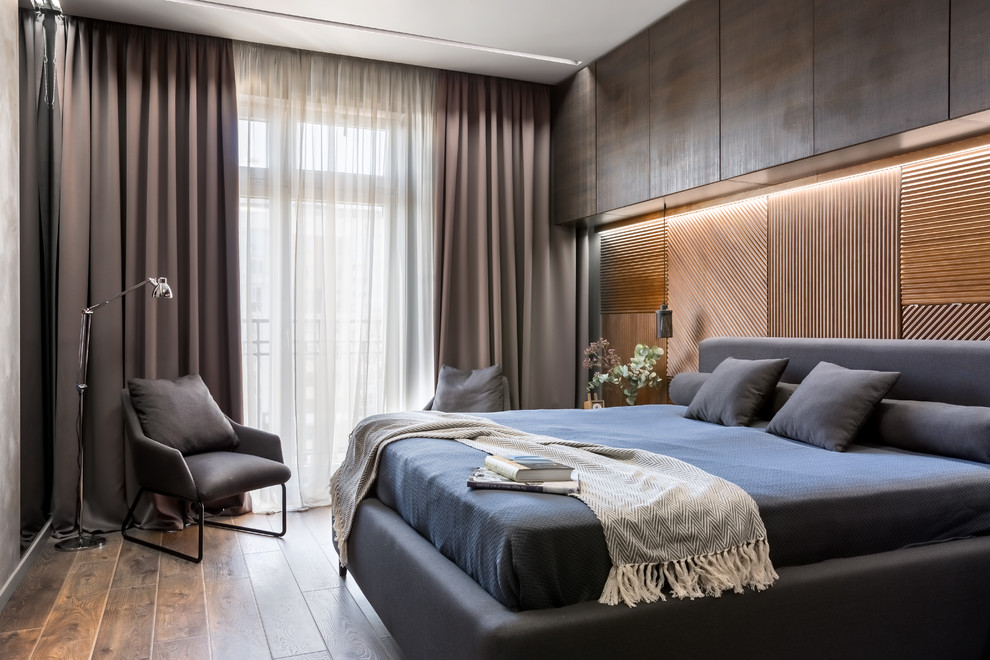 Design ideas for a medium sized contemporary master bedroom in Saint Petersburg with grey walls, laminate floors, brown floors and feature lighting.