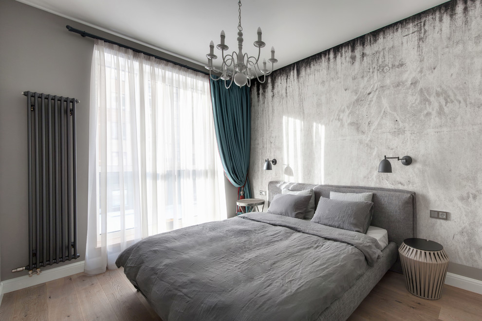 Immagine di una piccola camera matrimoniale design con pareti grigie e parquet chiaro